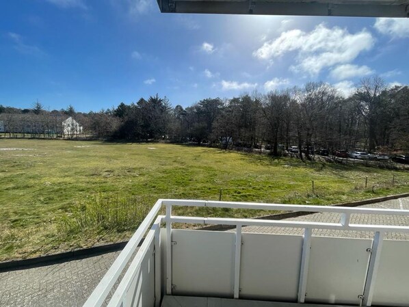 A grassy field with a white fence and a building in the background.