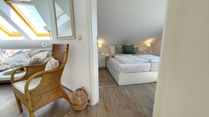 Une chambre à coucher avec un lit, une chaise en osier, une table de chevet et une lampe.
