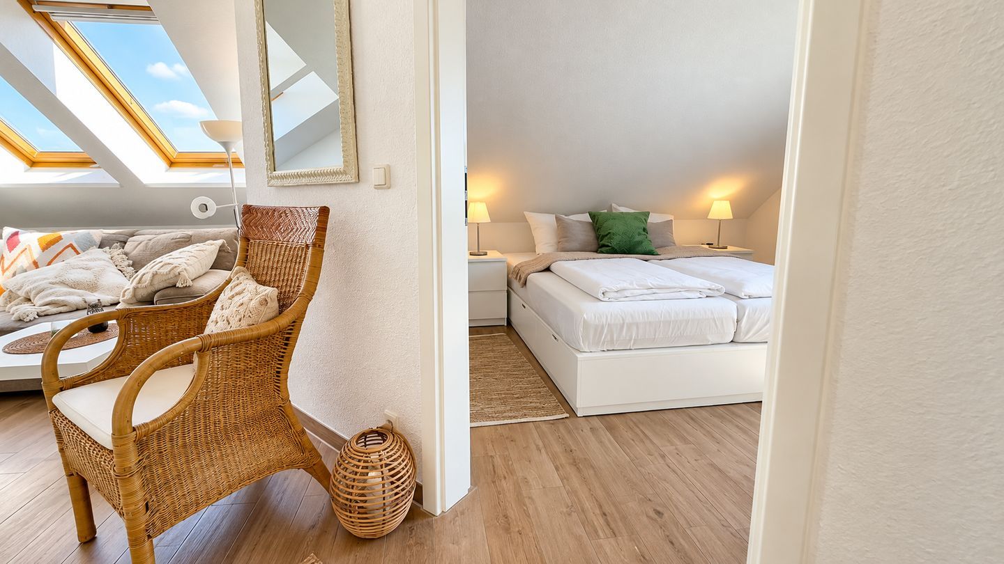 Ein Schlafzimmer mit einem Bett, einem Sessel, einem Nachttisch und einer Lampe.