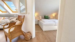 Een slaapkamer met een bed, een stoel, een nachtkastje en een lamp.