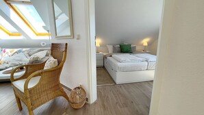 A bedroom with a bed, a wicker chair, a bedside table, and a lamp. - Kirsten 5 - Cozy vacation apartment close to the beach for up to 4 people - House (Cuxhaven)