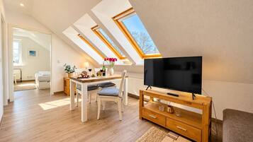 Ein modernes Wohnzimmer mit Flachbildfernseher, Holzmöbeln und Oberlichtern.
