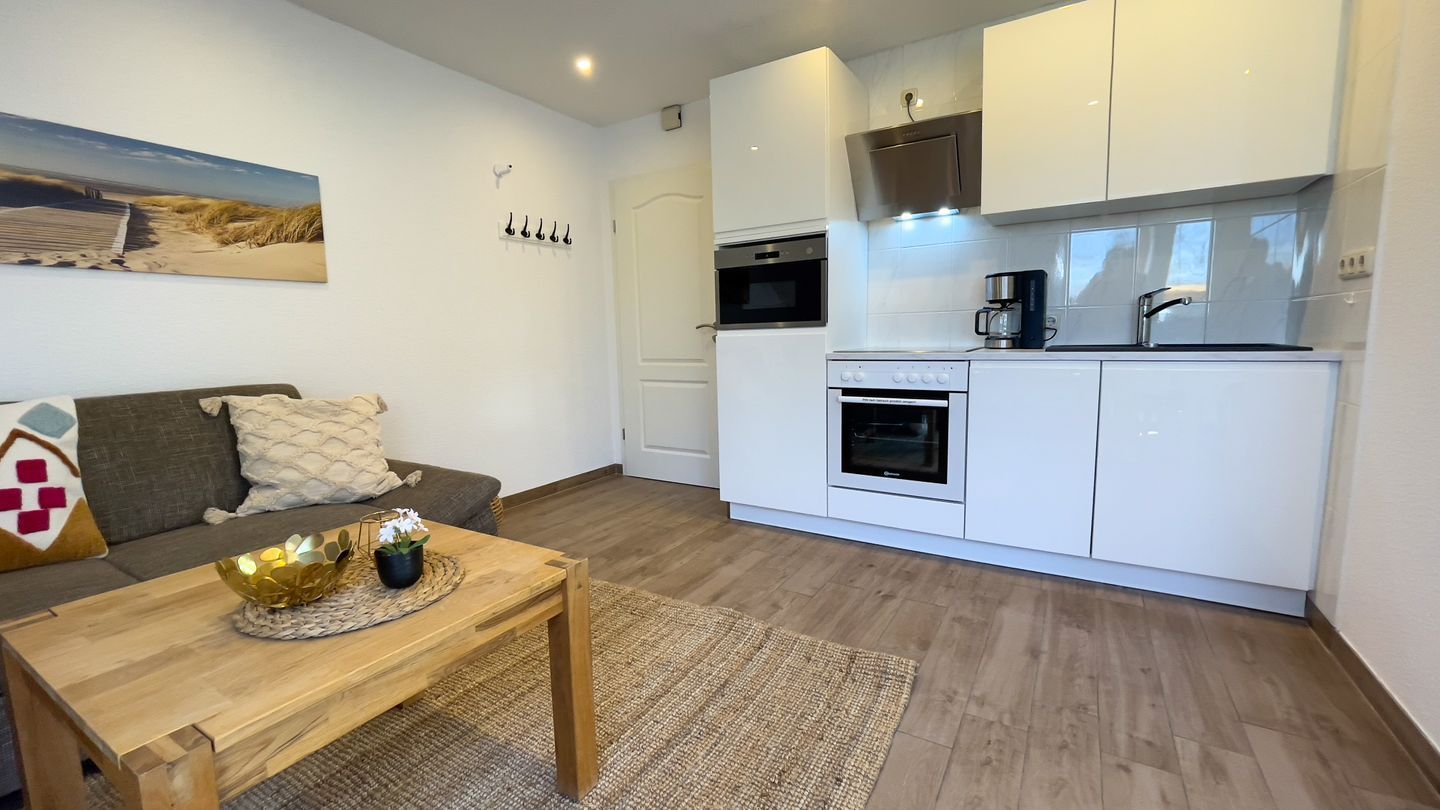 A compact living space with a kitchenette, a dining area with a wooden table, and a sofa.