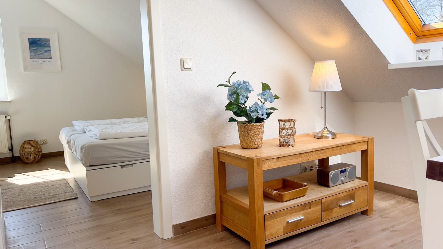 Ein Schlafzimmer mit Bett, Nachttisch, Lampe und einer an der Wand befestigten Ablage.