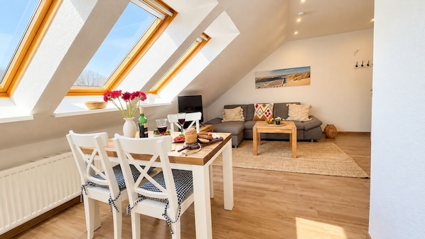 A modern living room with a dining area, featuring a sofa, a coffee table, and a dining table with chairs.