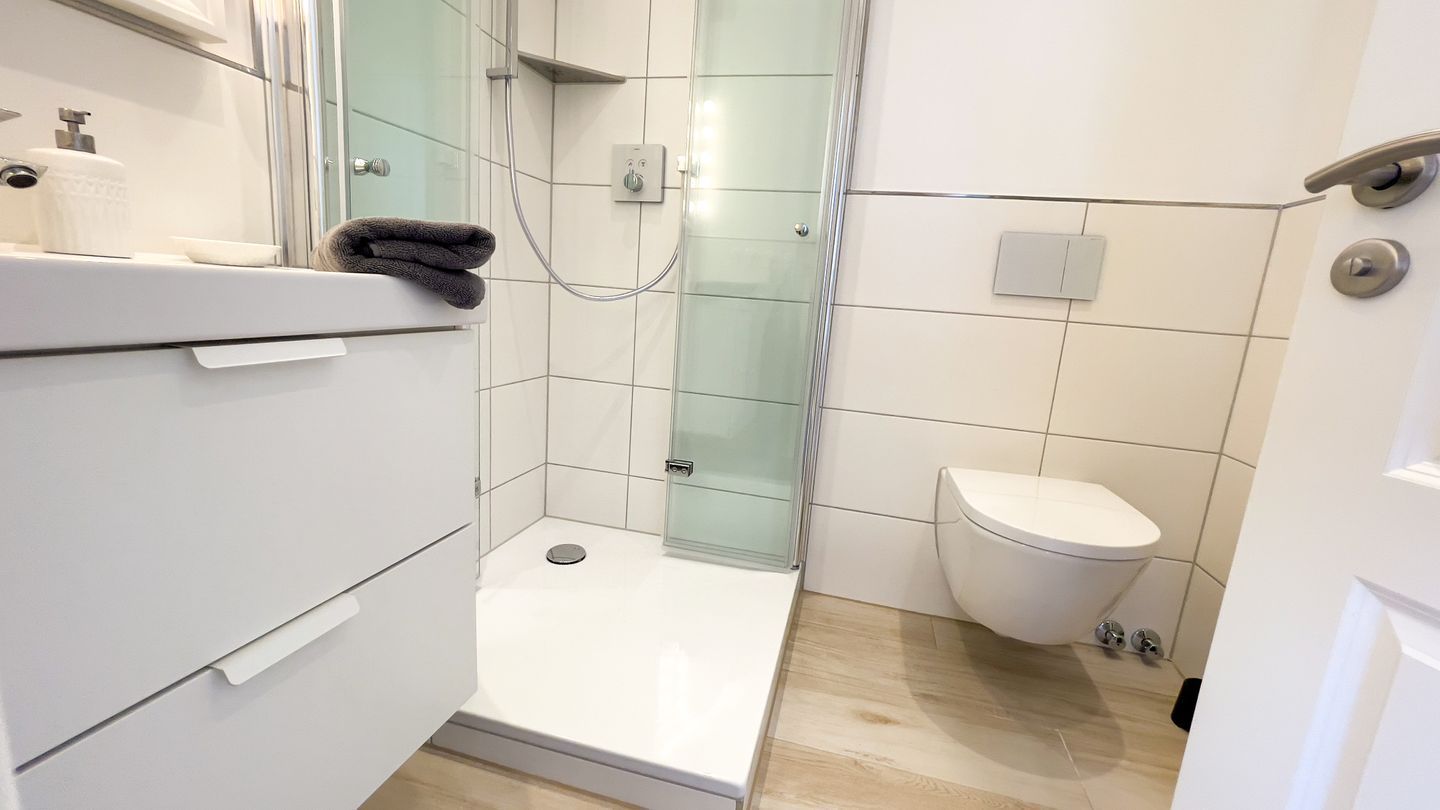 A modern bathroom with a shower, toilet, and a sink area.