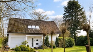 A two-story house with a tiled roof, a garage, and a well-maintained lawn.