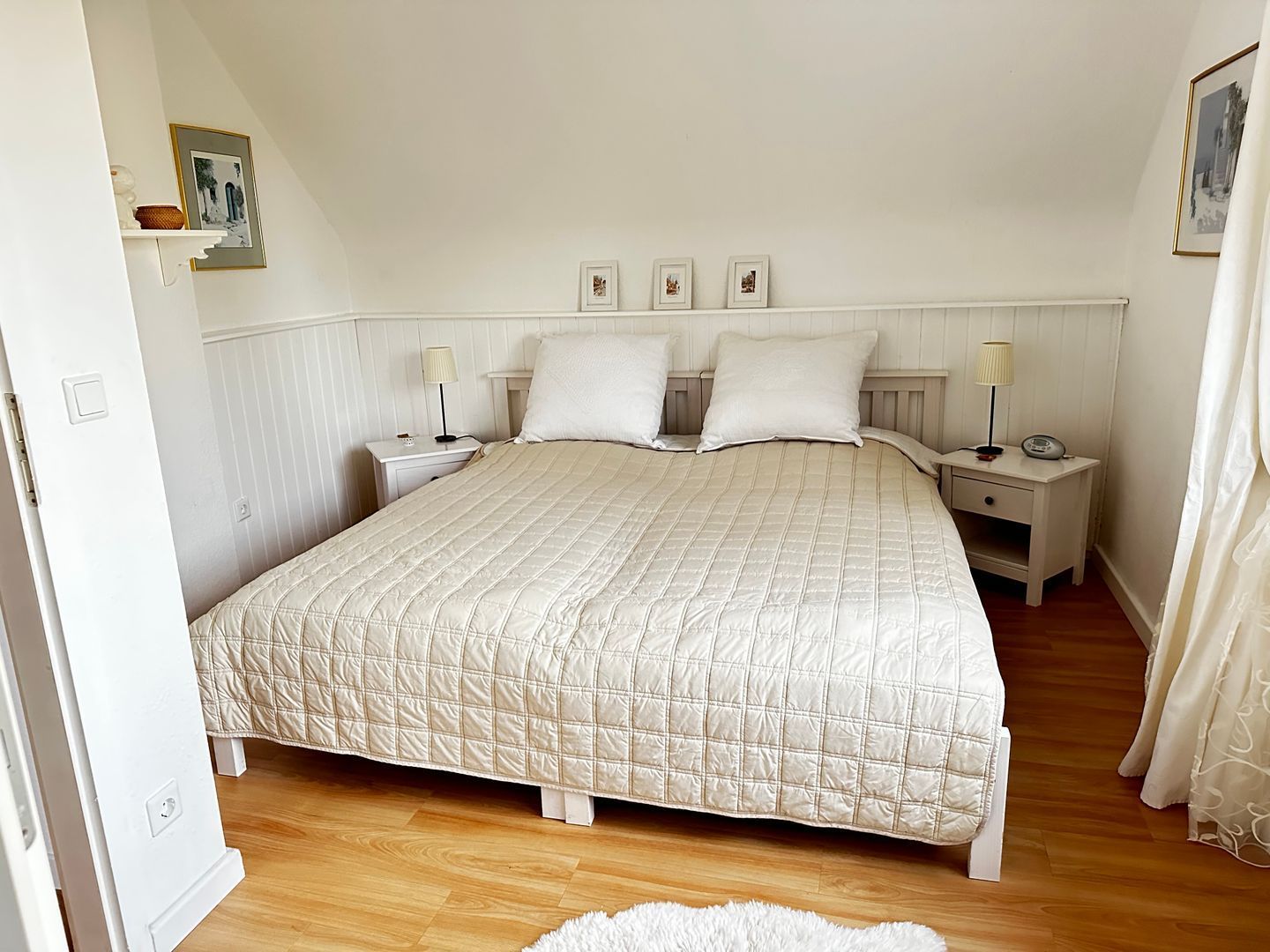 Ein Schlafzimmer mit einem großen Bett, zwei Nachttischen, einem Schranken und einer Heizung.