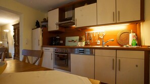 A kitchen with wooden cabinets, a stove, and various kitchen utensils. - Großzügige, Gemütliche Ferienwohnung für bis zu 6 Personen mit 3 Terrassen - Haus Wexler (Cuxhaven)