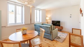 A modern living room with a wooden dining table, a sofa, and a TV. - D&S -JB Apartments - B (Oporto)