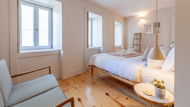 A bedroom with a bed, a chair, a bedside table, and a window. - D&S -JB Apartments - B (Oporto)