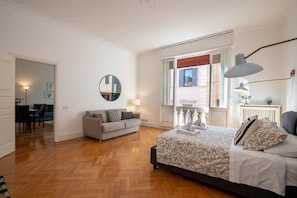 Ein Schlafzimmer mit einem Bett, einer Couch, einem runden Spiegel und einem Fenster mit Blick.