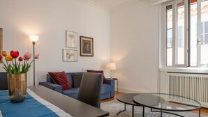 En moderne stue med sofa, sofabord i glas, spisebord med en vase med tulipaner og kunst på væggen.