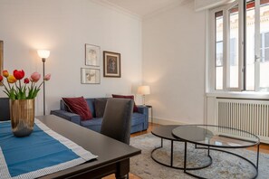 Un soggiorno moderno con un divano, un tavolino in vetro, un tavolo da pranzo con un vaso di tulipani e opere d'arte alle pareti.