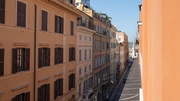A narrow street lined with multi-story buildings with balconies and shutters.
