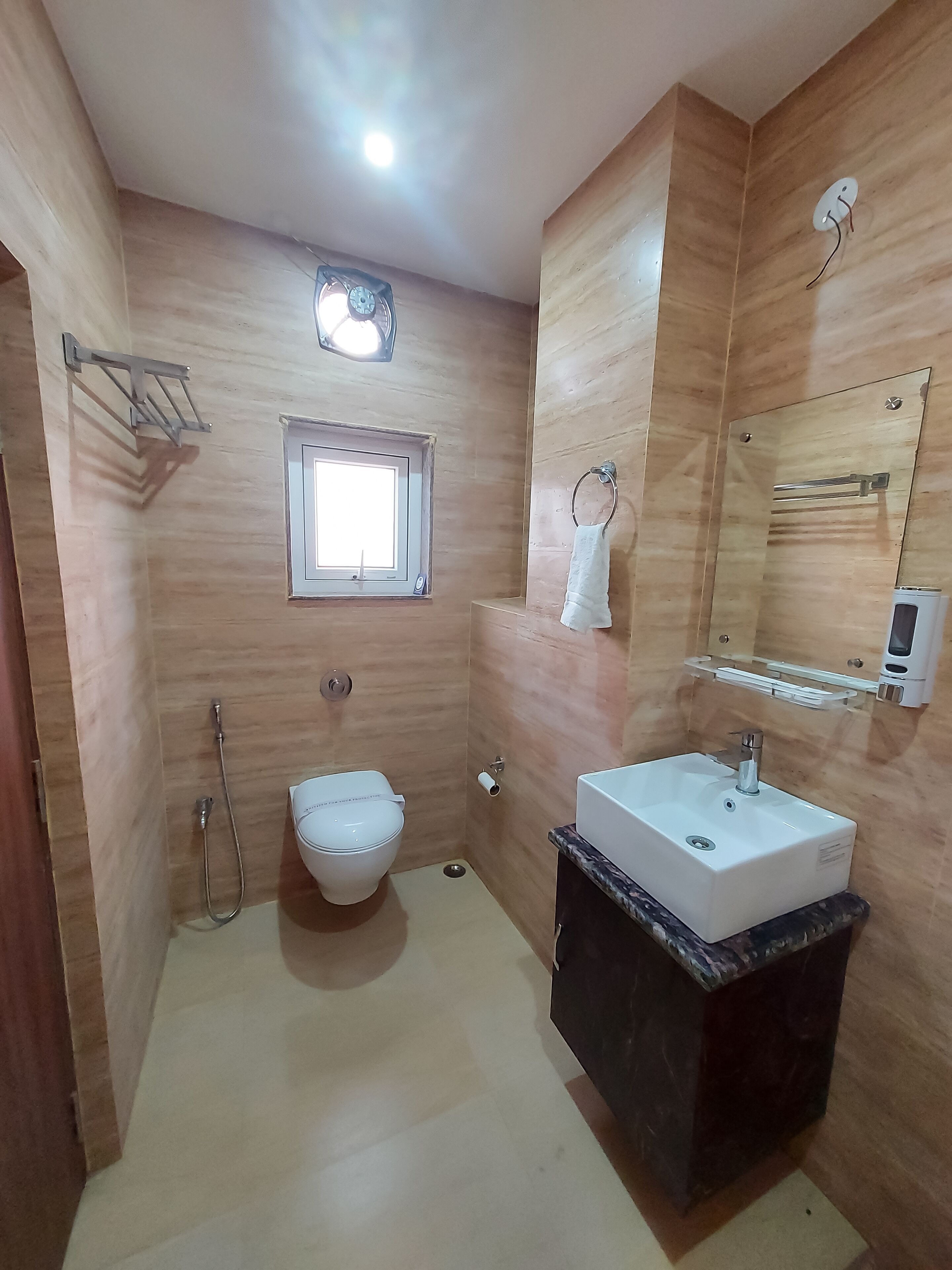 Une salle de bain comprenant des toilettes, un lavabo et une douche. Il y a une fenêtre au-dessus des toilettes et un porte-serviettes fixé au mur.
