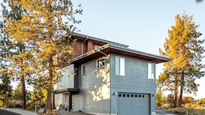 Ein zweigeschossiges Haus mit Garage, umgeben von Bäumen und einer Auffahrt.