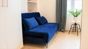 En blå soffa i ett rum med ett litet bord och en krukväxt.