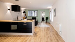 Une cuisine moderne dotée d’un grand îlot central, d’appareils électroménagers intégrés et donnant sur la salle à manger.