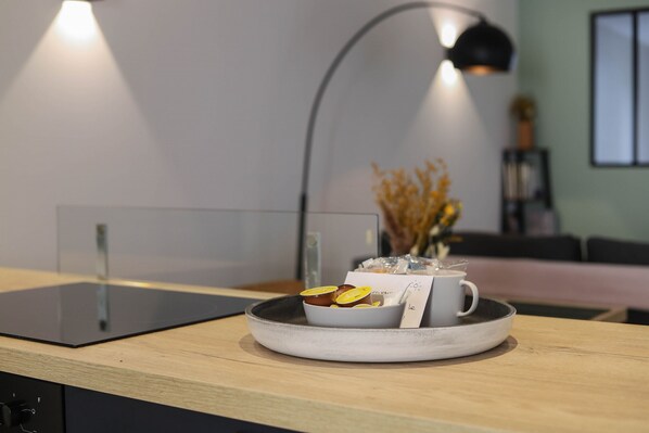 A modern kitchen with a built-in induction cooktop, a white bowl with food items, and a coffee cup on a tray.