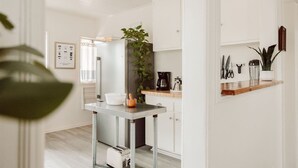 Eine moderne Küche mit einer zentralen Kochinsel, einer Kaffeemaschine und einem Blumentopf.