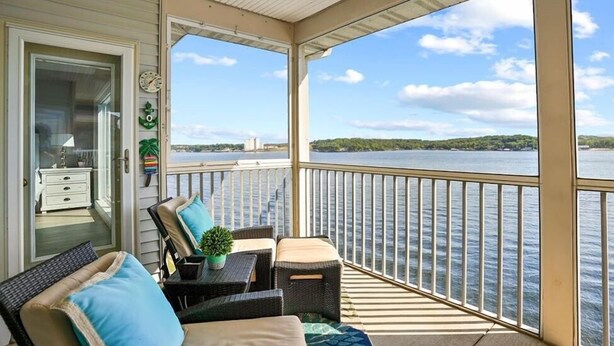 Ein überdachter Balkon mit Korbmöbeln, einem kleinen Tisch und einem Blumentopf.