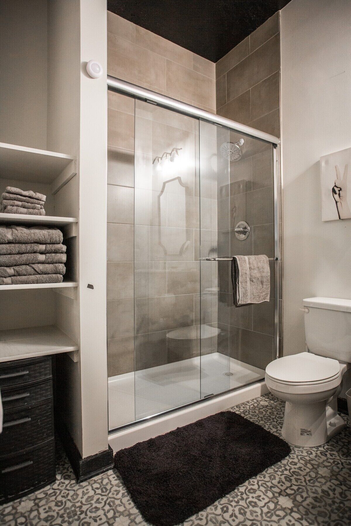 Een moderne badkamer met een douchecabine, toilet en handdoekhouder.