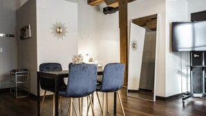 A dining area with a dark wooden table, four blue chairs, and decorative wall sconces.