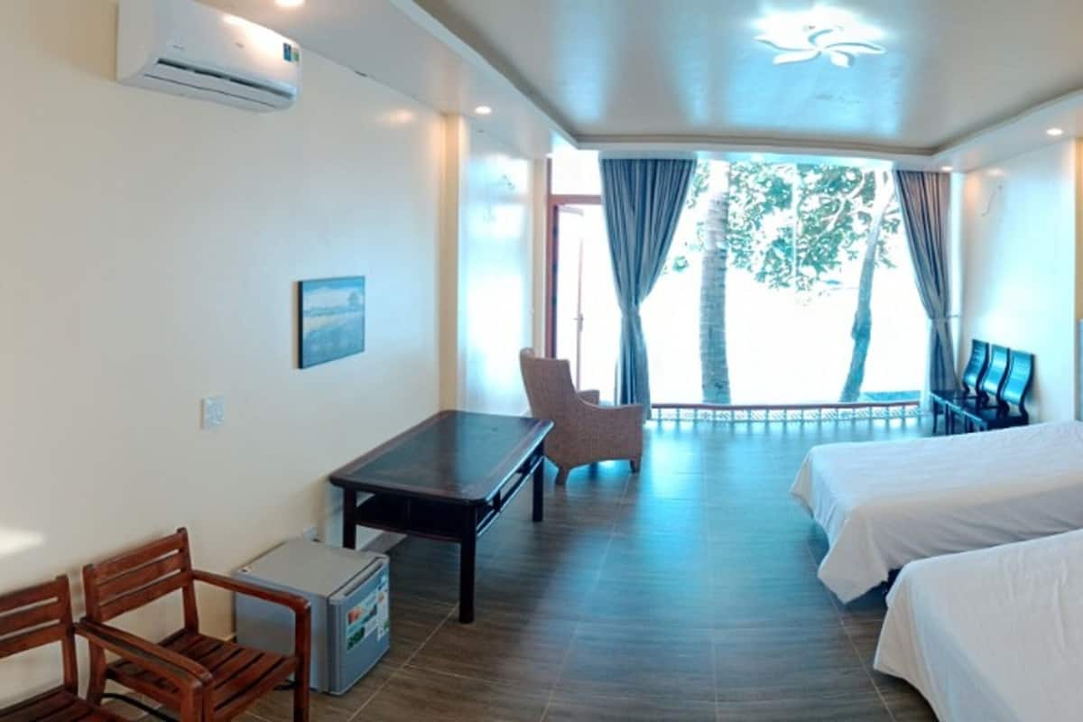 A hotel room with two beds, a desk, a chair, a small table, and a window with curtains.