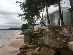 A beachfront property with large rocks, a building with a large window, and a view of the sea. - Phu Quoc Harbour View Villa (Phu Quoc)