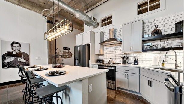 A modern kitchen with white cabinetry, stainless steel appliances, and a central island with bar stools. - The Crossing at 202- Downtown Waco/ Steps to Silos (Waco)