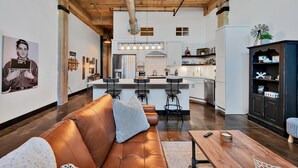 A modern kitchen with white cabinets, a central island, and bar stools. - The Crossing at 202- Downtown Waco/ Steps to Silos (Waco)