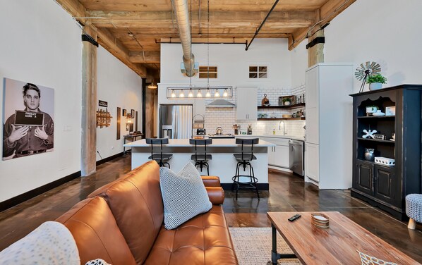 Une cuisine moderne avec des meubles blancs, un îlot central et des tabourets de bar.