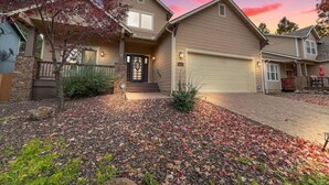 A two-story house with a garage, a front porch, and a landscaped front yard with fallen leaves.