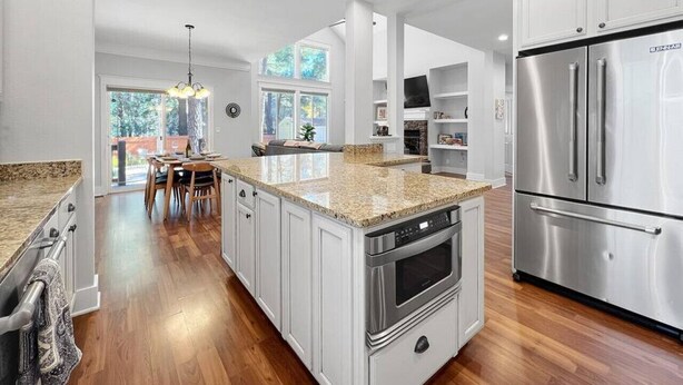 A modern kitchen with white cabinetry, stainless steel appliances, and a granite countertop.