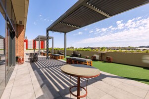 An outdoor patio with seating, a covered area, and a view of the cityscape.