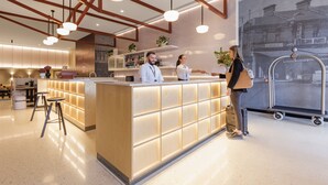 A modern hotel lobby with a reception desk, bar area, and seating. - Veriu Queen Victoria Market (Melbourne)