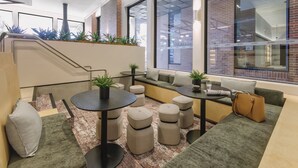 A modern lounge area with seating, tables, and a staircase. - Veriu Queen Victoria Market (Melbourne)