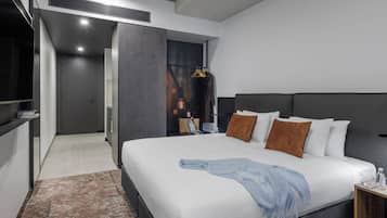 Ein modernes Hotelzimmer mit einem großen Bett, einem Nachttisch, einem Kleiderschrank und einem durchgegangenen Tür sichtbaren Badezimmer.