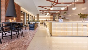 A modern restaurant with a bar area, a reception desk, and a seating area with tables and chairs. - Veriu Queen Victoria Market (Melbourne)