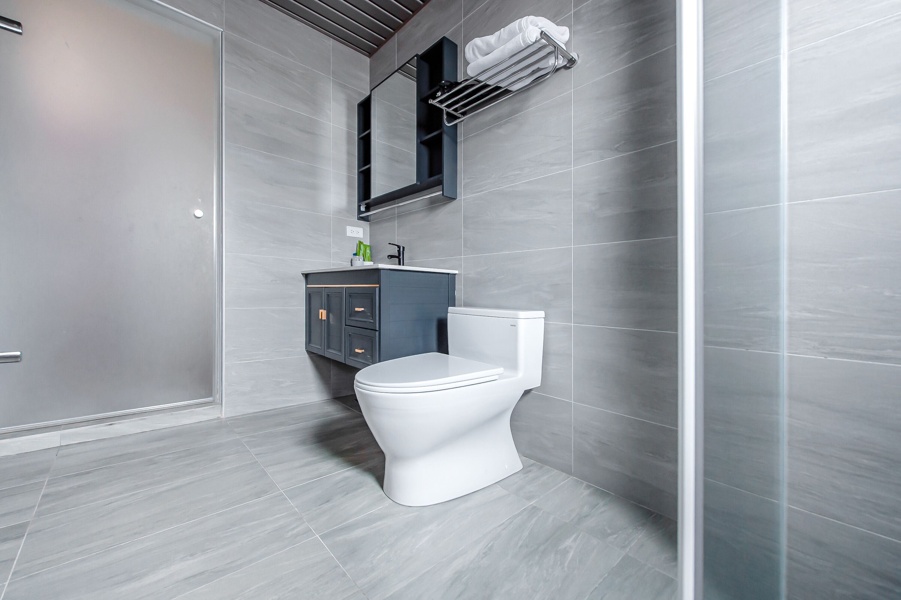 A modern bathroom with a toilet, vanity, and a towel rack.