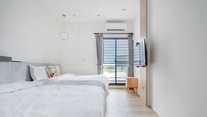 A modern hotel room with a large bed, a TV mounted on the wall, and a sliding glass door leading to a balcony. - Wenshui (Jiaoxi)