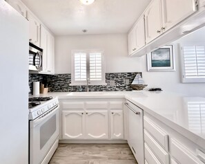 A kitchen with white cabinets, a stove, and a tiled backsplash.