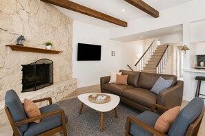 A living room with a stone fireplace, a brown leather sofa, and two armchairs. - Beach House -Harbor Views -Magnificient RoofDeck! (Oxnard)