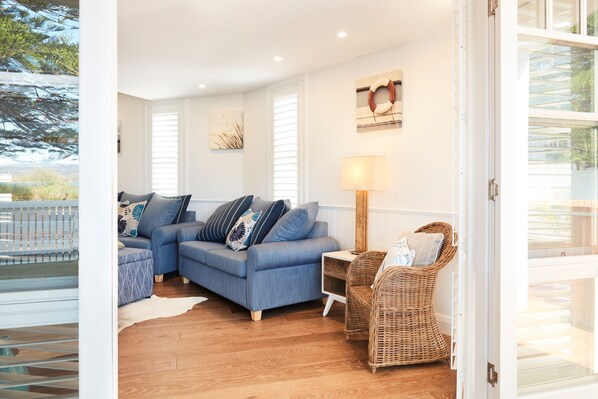 A living room with a blue sofa, a wicker chair, and a lamp.