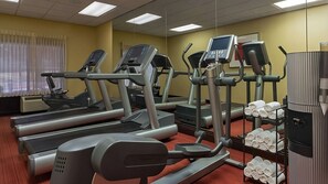 Een fitnessruimte met loopbanden, elliptische trainers en een handdoekenrek.