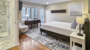 A bedroom with a bed, a desk, a chair, a lamp, and a window with blinds. - Westport Gem - walk to shops, dining, town center, pet-friendly (Westport)