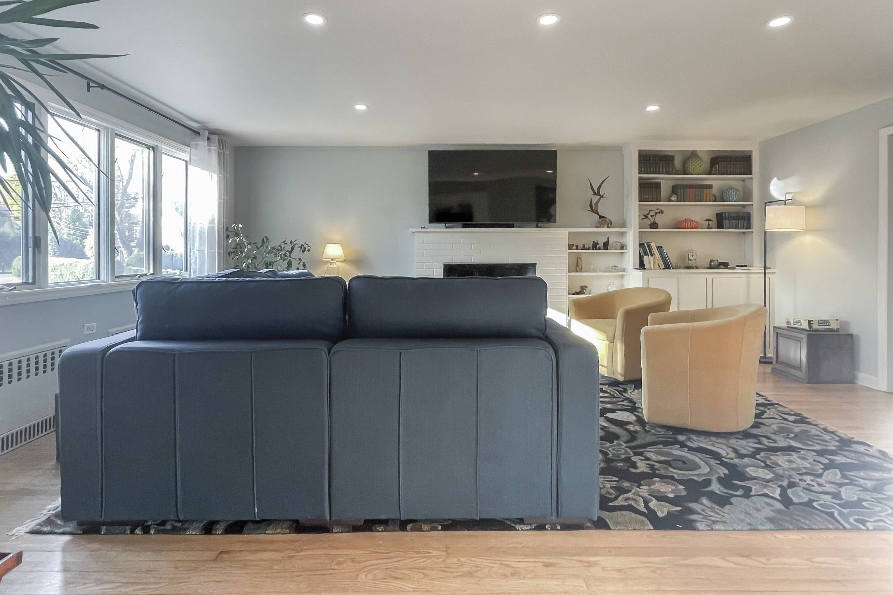 A modern living room with a grey sofa, a coffee table, and a TV on a white fireplace mantel.