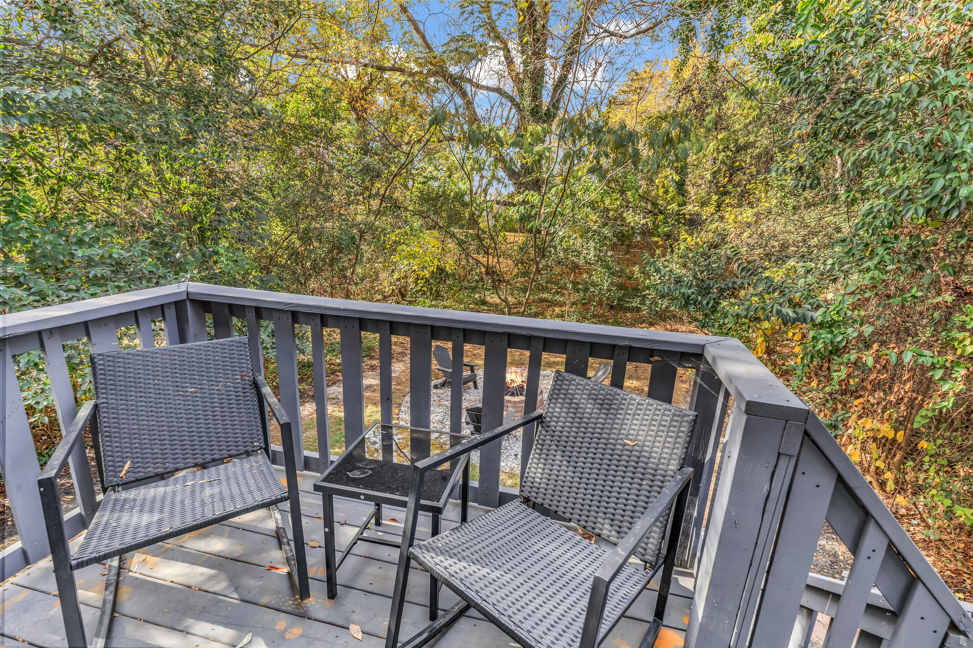 A wooden deck with two metal chairs and a small table.
