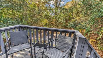 A wooden deck with two metal chairs and a small table.
